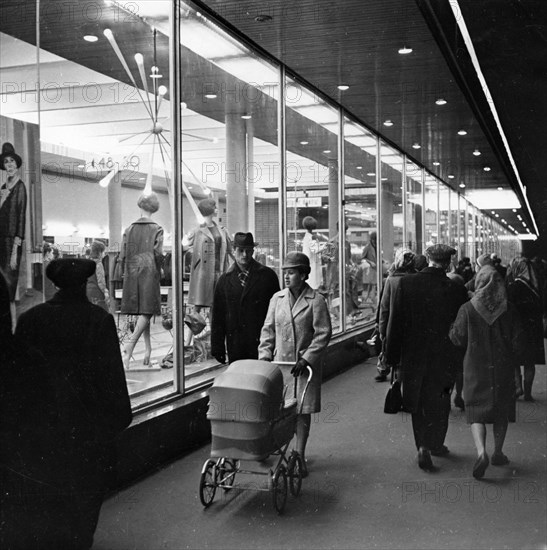 A young family passing by the windows of the lyudmila shop in tchkalov street in moscow, 1950s.