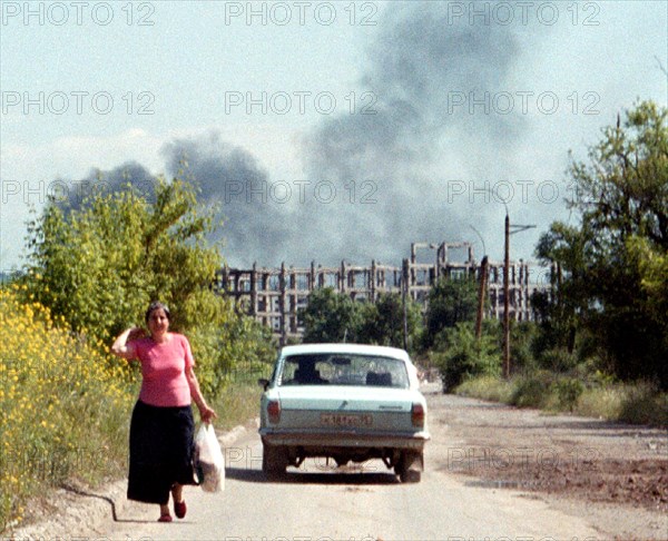 Chechnya, russia, june 16, 2001, peaceful life in grozny borders upon remaines of the war, such as a view of ruins of the chechen gas and oil insitute (on the background), a train of smoke from a burning oil well etc.