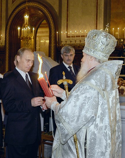 Patriarch of moscow and all russia alexy ll handing to president of russia vladimir putin a candle lit of the holy fire brought from jerusalem, at the easter service at the christ the saviour cathedral in moscow, april 11, 2004.