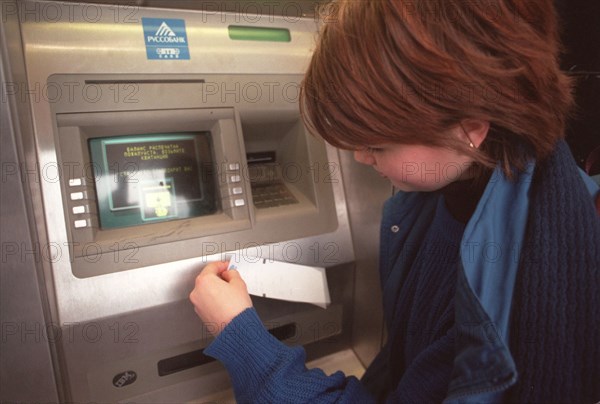 A russian girl at a cash dispenser in novy arbat street downtown moscow, russians who use plastic cards may face difficulties during the new year celebrations as in the days of the holiday all cash dispensers in the country will have to be adjusted for new banknotes because of future money denomination reform to start on jan,1st, 1998.