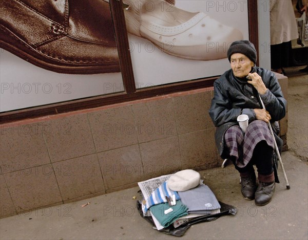 Moscow, russia, a poor old woman sells knitted scarves in front of a shoe store window, september 2005.