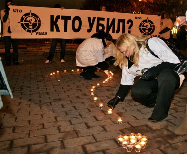 Mourners arrange lit candles into a large question mark in front of a banner reading 'who's the killer?' during a rally in pushkin square, marking the 40 day anniversary of anna politkovskaya's death, moscow, russia, november 15, 2006.