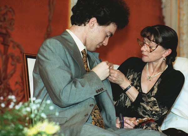 Moscow, russia 6/26/97: famous ballet dancer yekaterina maximova /right/ attaches a badge of russian independent 'triumph' prize to prominent russian pianist yevgeny kisin who lives now in the united states, the ceremony was held at bethoven hall of the bolshoi theatre, the prize set up in 1992 mark outstanding achievements in literature and arts, sponsor of this prize is js'logovaz'.