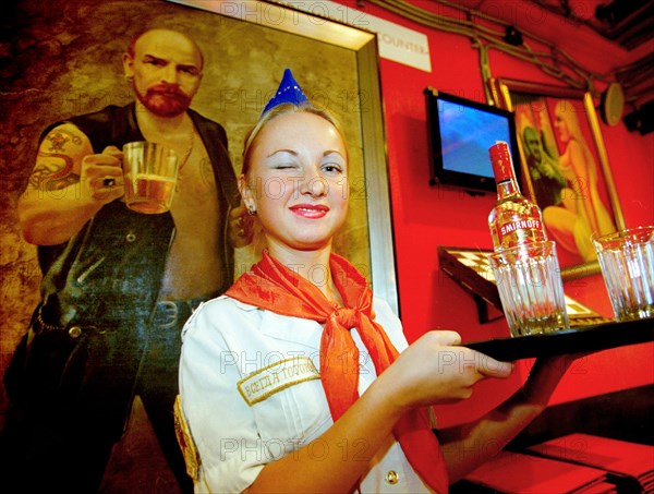 Waitress serving beer at a popular st, petersburg restaurant ilyich's call (lenin's mating call) with theme of soviet era nostalgia, waitress is dressed in the uniform of the young pioneers (soviet girl scouts), 2004.