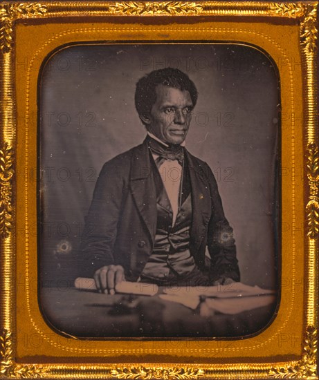 Beverly Page Yates, half-length portrait, facing slightly right, seated at table, holding rolled piece of paper