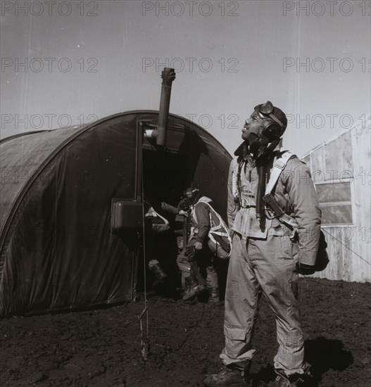 Black fighter pilot series--pilot with parachute room in background, Ramitelli, Italy