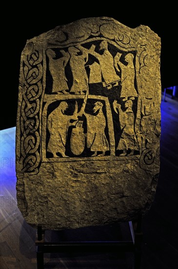 Runic Stone. Men with drinking horns and two men fighting with swords.