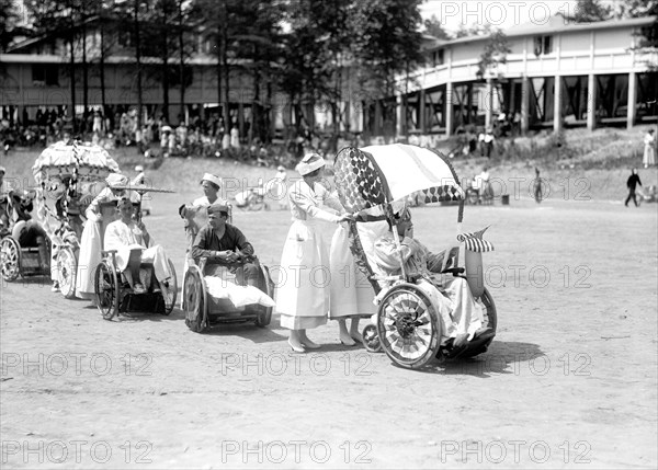 Wounded WW I soldiers at Walter Reed Hospital participate in a 4th of July wheel chair parade circa 1919 .