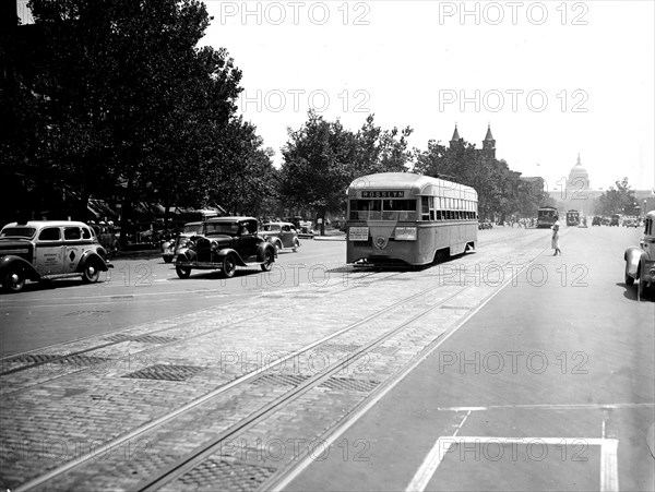 Taxi, streetcar, and automobiles on Washington D.C. street with Capitol in background circa 1936.