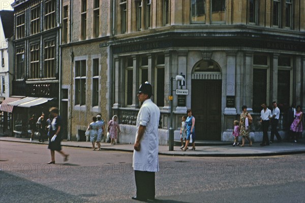 Bobby in London standing in the middle of a street in front of a Barclays Bank Building circa 1970.