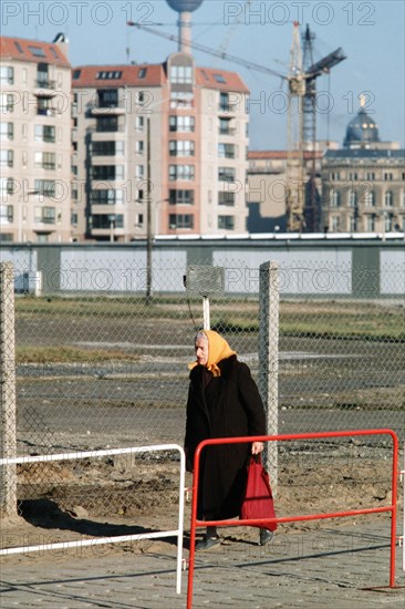 1989 - An old woman walks through the newly created opening in the Berlin Wall at Potsdamer Platz..