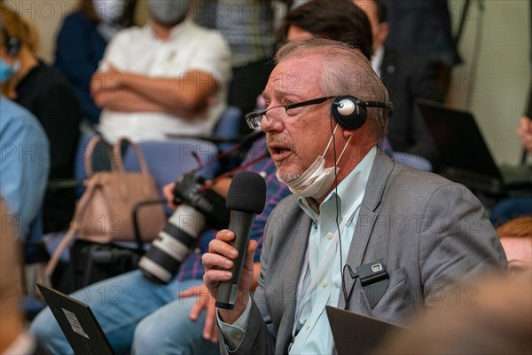 A reporter takes his mask off to ask a question