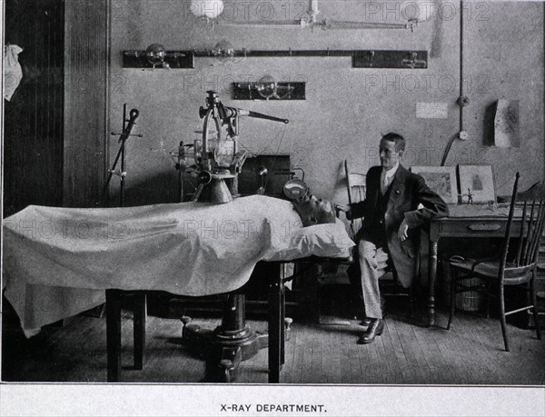 African American man is on a table covered with a sheet lying beneath an x-ray machine