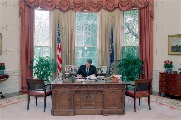 President Reagan working at his Oval Office desk.