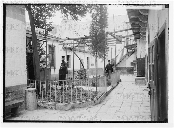 Two Orthodox priests at the Greek Convent near the Church of the Holy Sepulchre in Israel, the library exterior ca. 1920