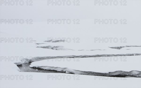 A creek winds through a snowy valley. Antler Creek in Hayden Valley in Yellowstone National Park; Date:  3 February 2015