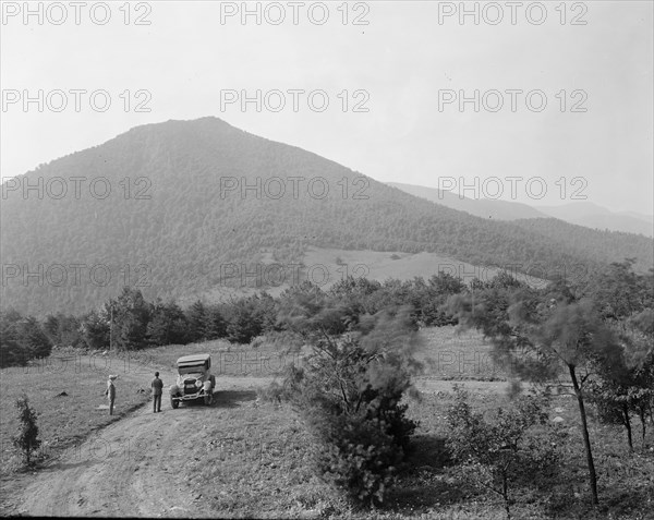 Two men outside a car on a rural road ca.  between 1910 and 1926