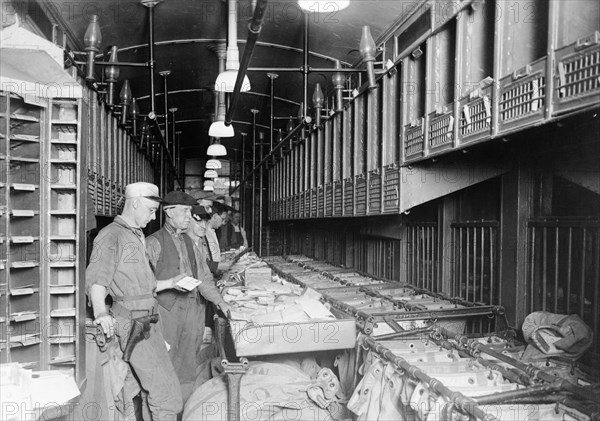 Men working in a railway mail train car ca. 1909