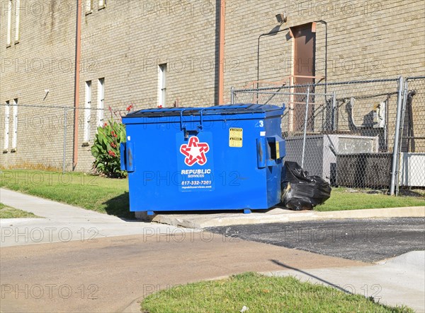 A close up a blue Republic Services dumpster behind a church building in Euless, TX