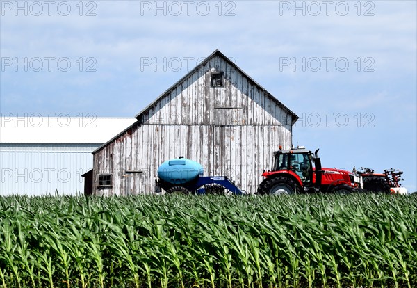 Red tractor and a barn on a farm south of Crescent City, Illinois on U.S. Route 49; corn in the foreground