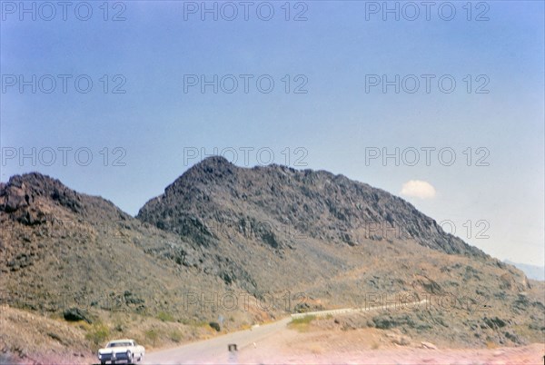 Car driving down a rural road in Nevada ca. 1966