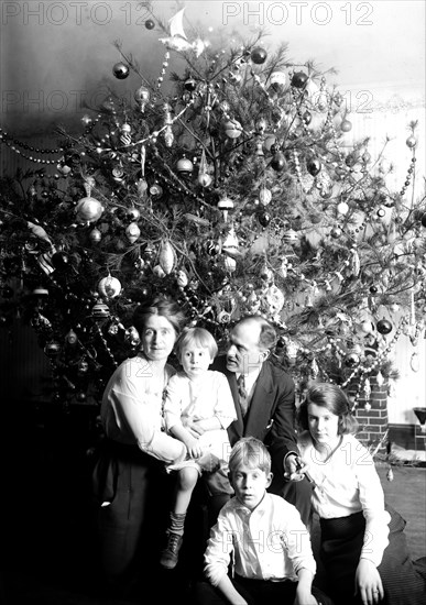 Family in front of their Christmas tree at home in early 1900s ca. 1921