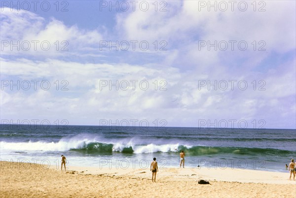Tourists / beachgoers enjoying the surf and beach in Oahu Hawaii ca. 1973