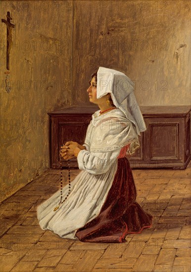 woman prays on her knees in front of a cross on the wall