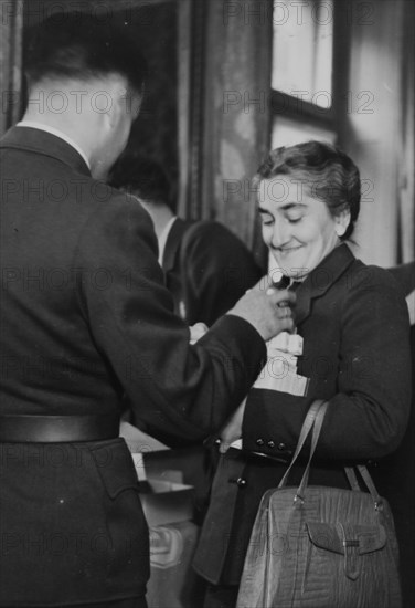 A nurse receiving her emergency ration: chocolate, Ovomaltine, tinned food, soup cubes, crispbread and pastilles of vitamin B and C.