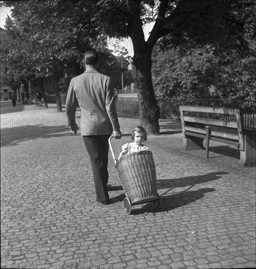 Man transporting girl in a shopping trolley, 1941.