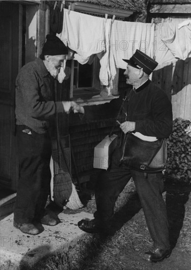 Farmer saying hello to the postman at his door 1950.