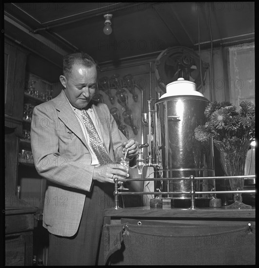 Heinz Ambuehl serving schnapps at his restaurant; Zell ca. 1948 .