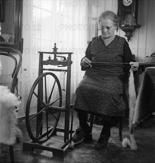 Woman sitting at spinning wheel 1946 .