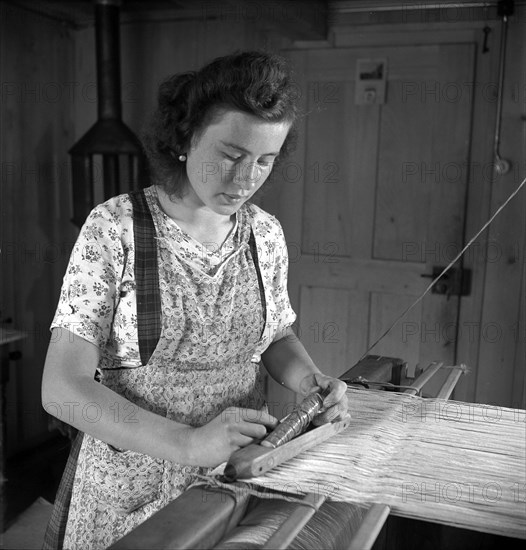 Young woman weaving bast fibre by hand loom, 1946 .