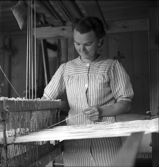 Young woman weaving bast fibre by hand loom, 1946 .