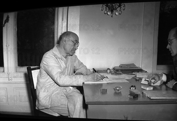 André Gide writing in a hotel room, 1947