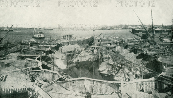 The photo dates to before 1922. The caption reads: A general view of the cause of the Spanish-American War, the cofferdam built to permit a thorough examination, which proved the theory that the disaster was caused by a sunken mine or torpedo. After this inspection, the wreck was cut up, floated out, and sunk in the Gulf of Mexico.