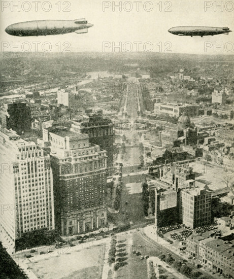 This photo dates to the early 1920s. Its caption reads: The ""Akron"" and the ""Los Angeles"" in Flight. At the left is the great dirigible Akron, built in American yards as a fighting ship for the Navy; 785 feet long, 132 feet in diameter. Following her is the Los Angeles, 656 feet long, 90 feet in diameter. The photograph was taken as the giant airships sailed over Philadelphia.