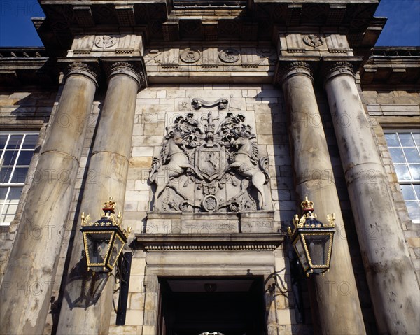 SCOTLAND, Lothian, Edinburgh, Holyrood House. Ornate crest above door with stone columns and wall lamps