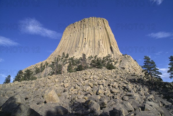 USA, Wyoming, Devils Tower, 867ft high National Monument of volcanic outcrop with bolders leading down to the foreground