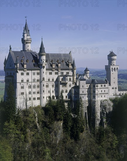 GERMANY, Bavaria, Fussen, Neuschwanstein Castle of King Ludwig on a rocky hill amongst trees