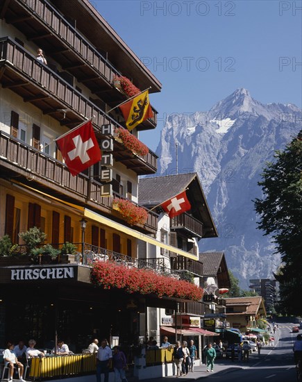 SWITZERLAND, Bern Oberland, Grindelwald, Main street and hotel e distancewith flags on the balconies and a snowcapped mountain
