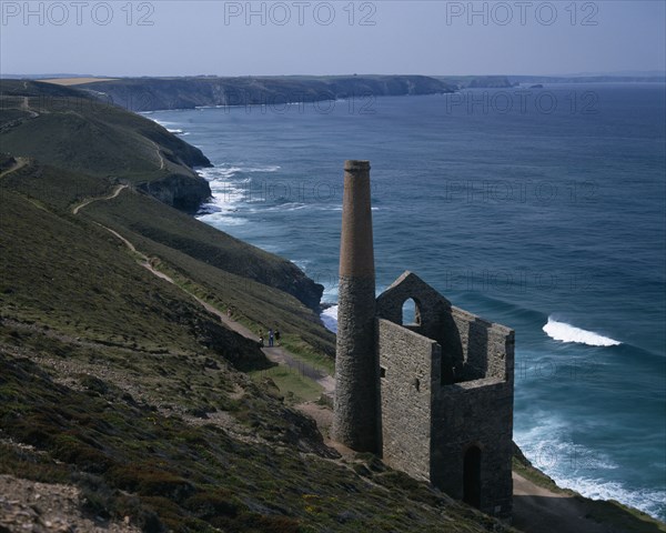 ENGLAND, Cornwall, St Agnes. Coastline with stone building and chimney next to coastal path