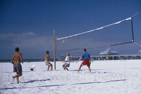 USA, Florida, Clearwater , People playing beach volleyball with small pier in the background