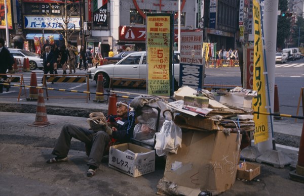 JAPAN, Honshu, Tokyo, Homeless man living on the street with his cardboard home at a busy road junction