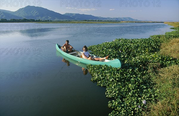 ZIMBABWE, Mashonaland, Mana Pools National Park, Couple fishing for bream in a canoe on the Zambezi River