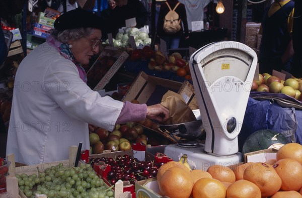 ENGLAND, London, Portobello Road. Fruit market with women stall holder near a weighing scales