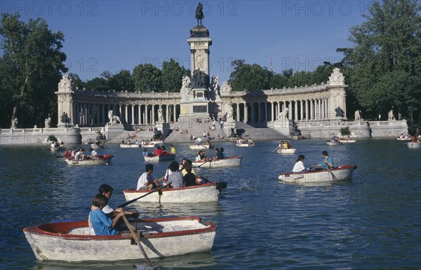 SPAIN, Madrid , El Retiro Park. View over the busy boating lake toward column with equestrian statue atop