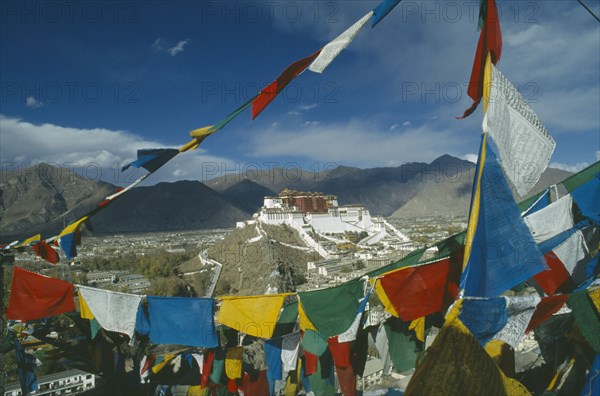TIBET, Lhasa, Potala Palace, View across valley through prayer flags towards the Potala set on the top of a hill