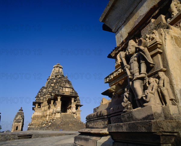 INDIA, Madhya Pradesh, Khajuraho, Vishvanath Temple and carved figures on stone base against blue sky